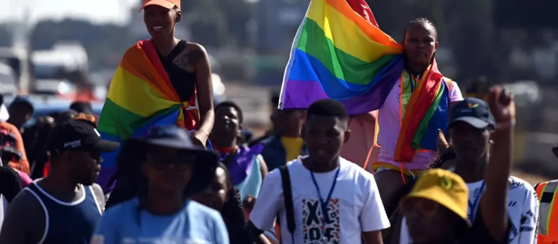 Des personnes brandissant des pancartes et des drapeaux arc-en-ciel lors de la marche des fiertés annuelle dans la capitale du Botswana en octobre 2023.  MONIRUL BHUIYAN / AFP